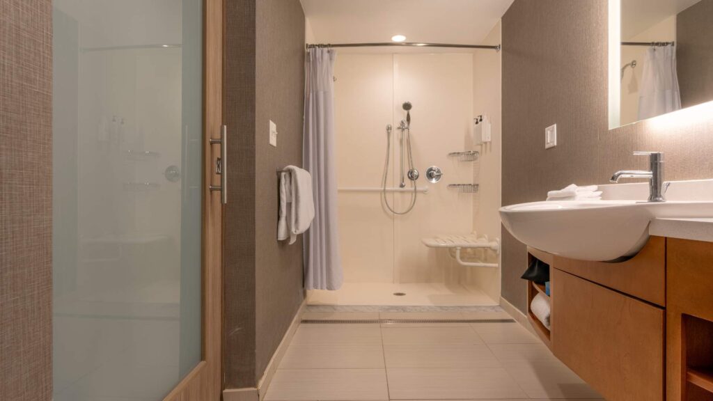 A newly remodeled ADA compliant bathroom with open shower and lowered sink