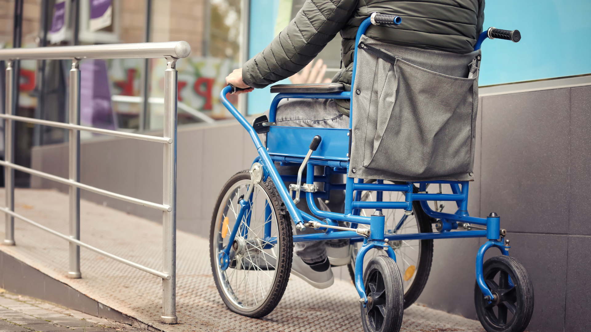 Man in wheelchair using wheelchair ramp outside of a store in Long Island, NY